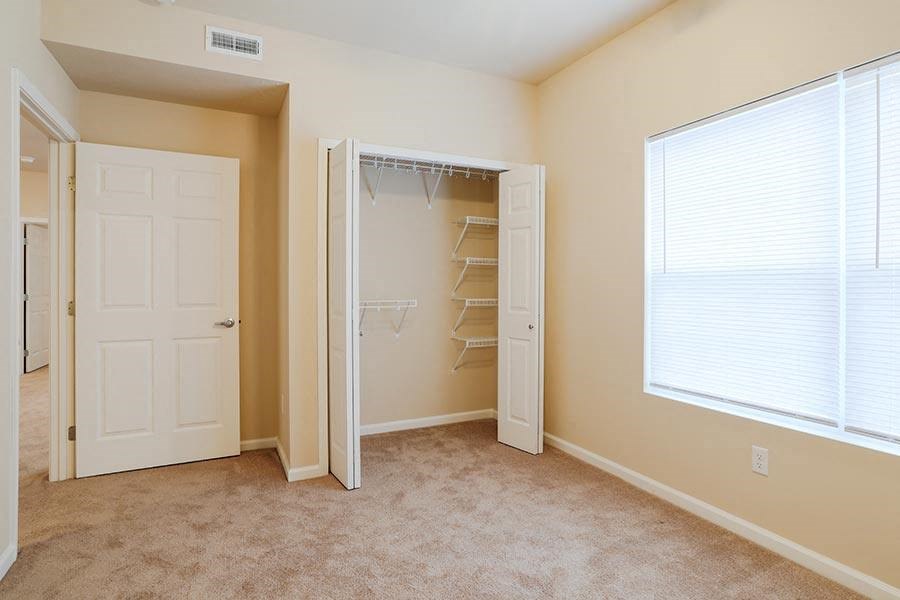 an empty bedroom with a closet and a window