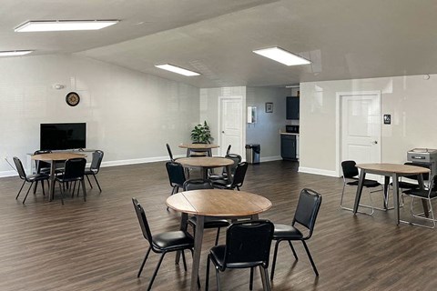 an empty room with tables and chairs and a television