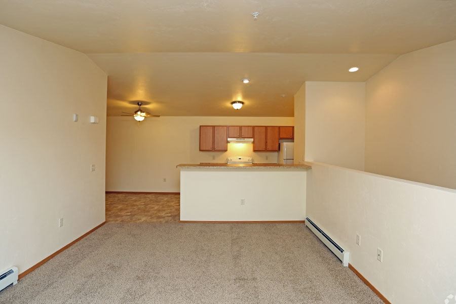 an empty living room and kitchen with a counter