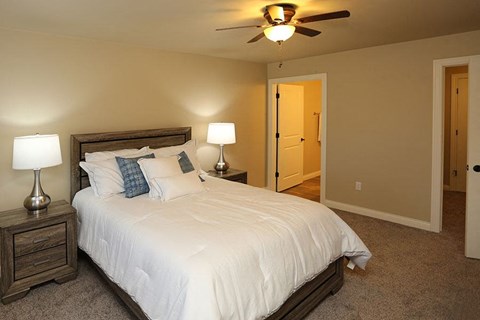 A bedroom with a bed, two lamps, and a ceiling fan.