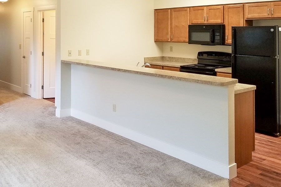 A kitchen with a black refrigerator and a white counter.