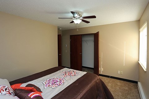 A bedroom with a bed and a ceiling fan.