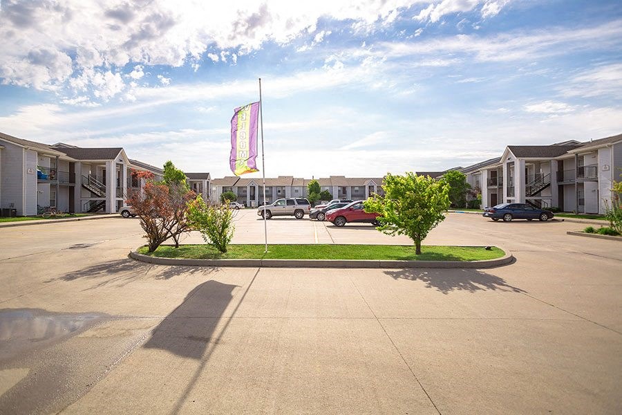 A parking lot with a flag in the background and a few cars parked.