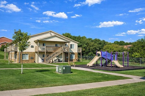 A playground with a slide and a building in the background.