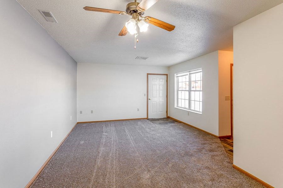 a empty living room with a ceiling fan and a door