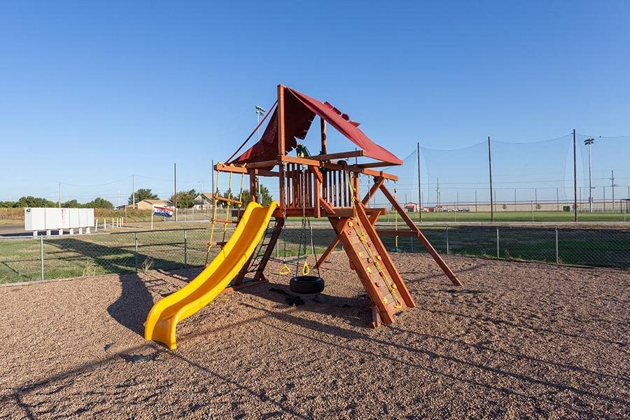 a swing set with a yellow slide in a playground