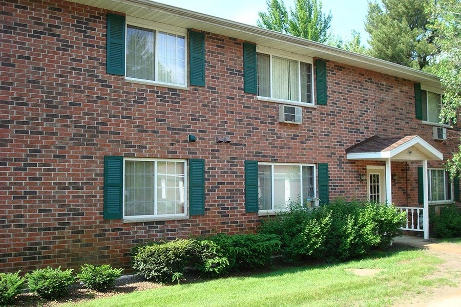 a brick house with green shuttered windows and a porch