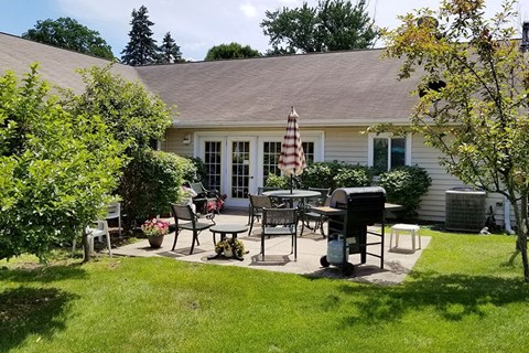 a backyard patio with tables and chairs and a grill