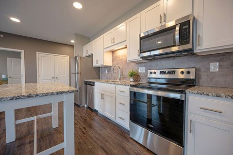 A kitchen with a granite countertop and stainless steel appliances.