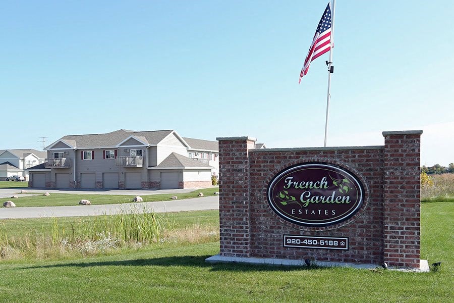 a sign for the front garden estates in front of an flag