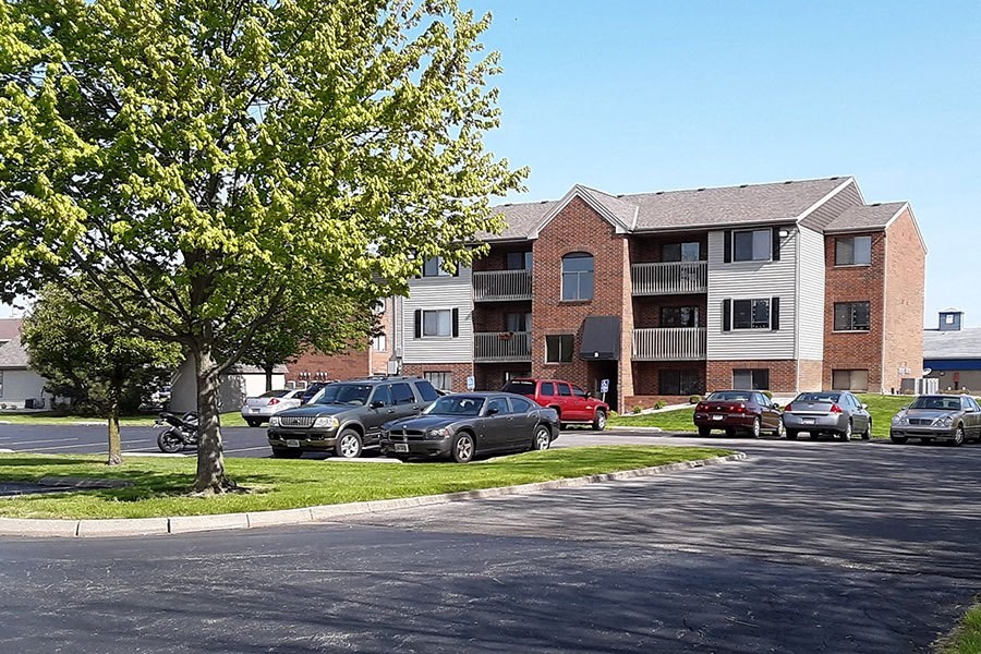 a street with cars parked in front of an apartment building