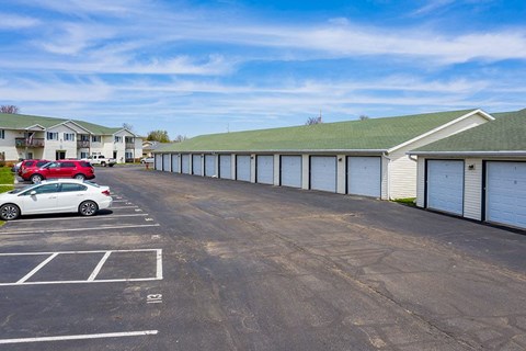a parking lot with garages and cars in front of a building