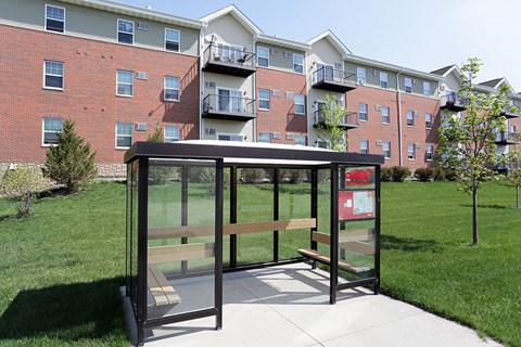 A bus stop with a bench in front of a brick building.