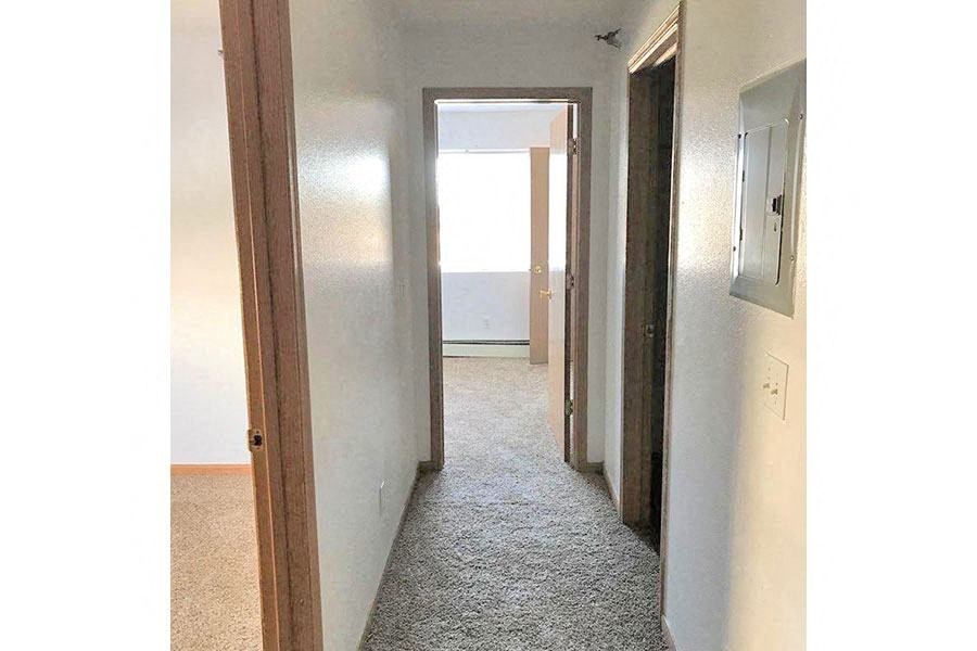 a hallway with a door to a room and a closet