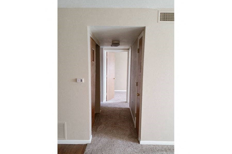 an empty hallway with a door to a bedroom and a closet