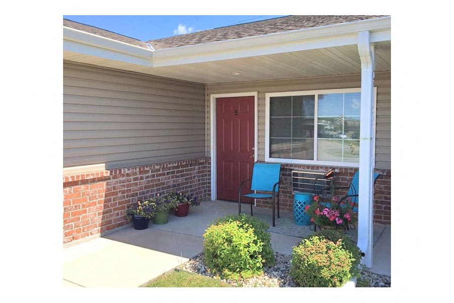 a porch in front of a house with a red door