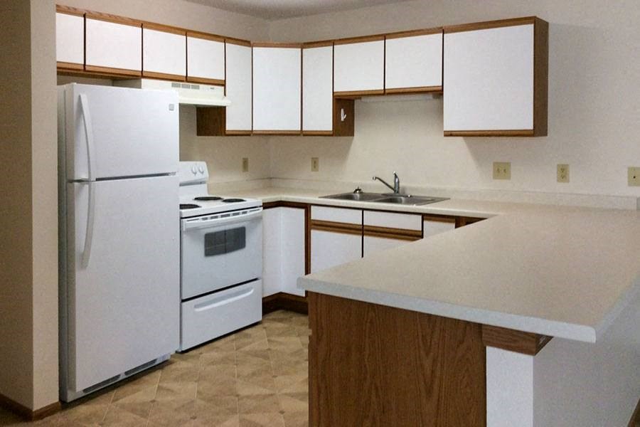 an empty kitchen with white appliances and white cabinets