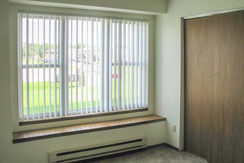 an empty room with a window with white blinds