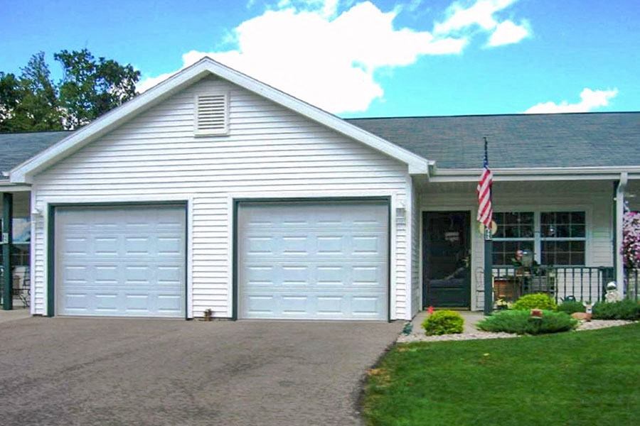 a white house with two garage doors and a flag