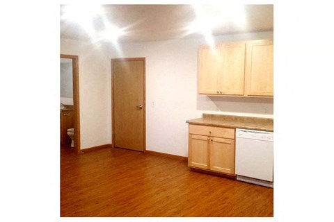 an empty kitchen with wooden floors and a door