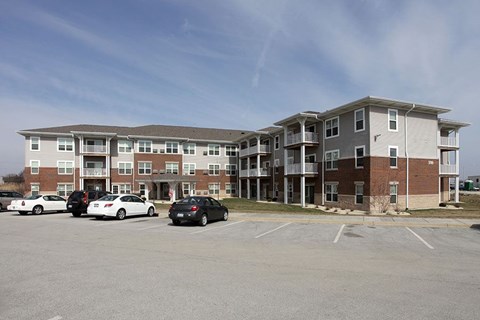 A black car is parked in a parking lot in front of a building.
