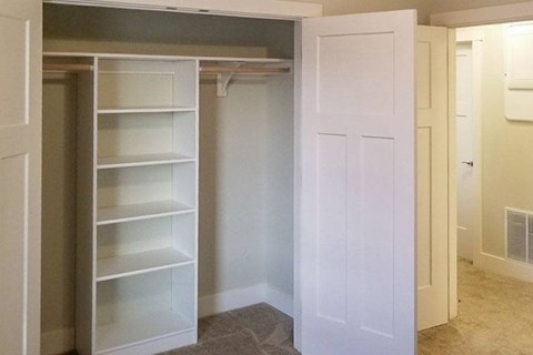 A white closet with shelves and a door open.