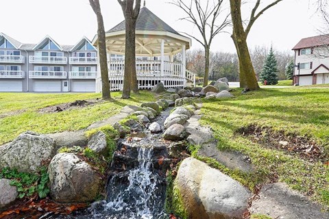 A small waterfall in a rock garden in front of a building.