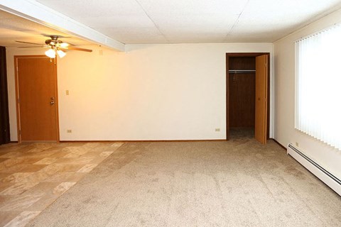 A room with a carpeted floor and a ceiling fan.