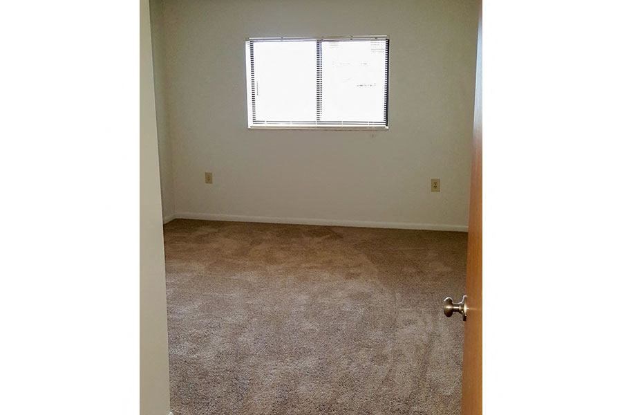 A room with a carpeted floor and a door.