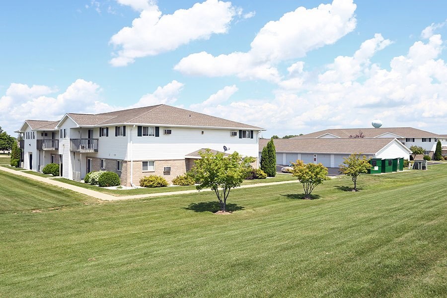A large white building with a brown roof and a green lawn in front.