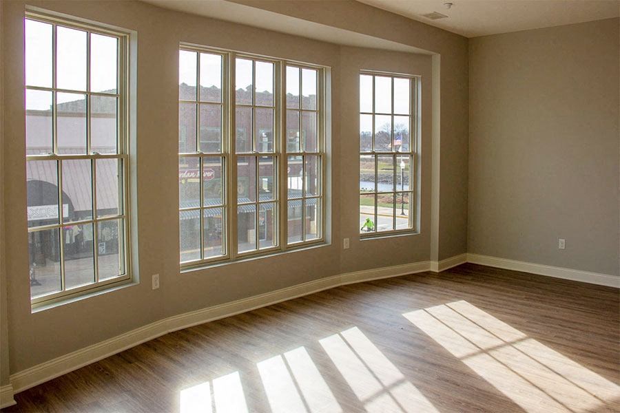 an empty living room with large windows and wooden floors