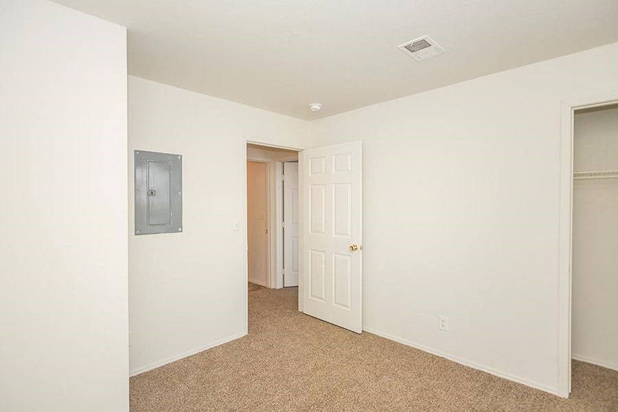 A room with a door and a light switch on the wall.