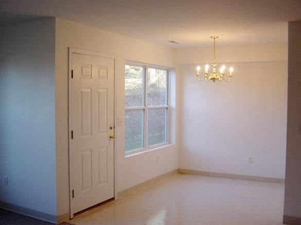 A white door is in a room with a chandelier.