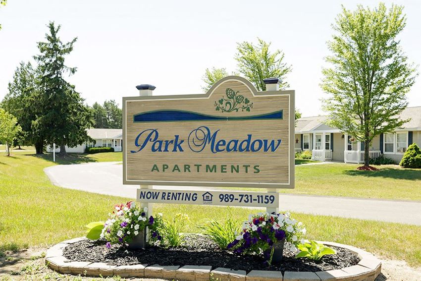 a park meadow apartments sign in front of a garden