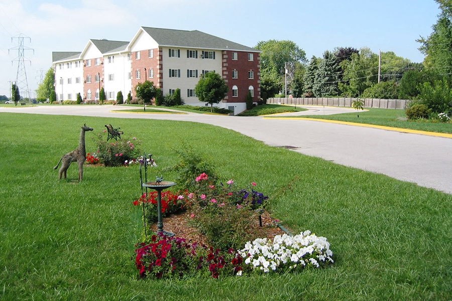 a flower garden in the grass in front of a building