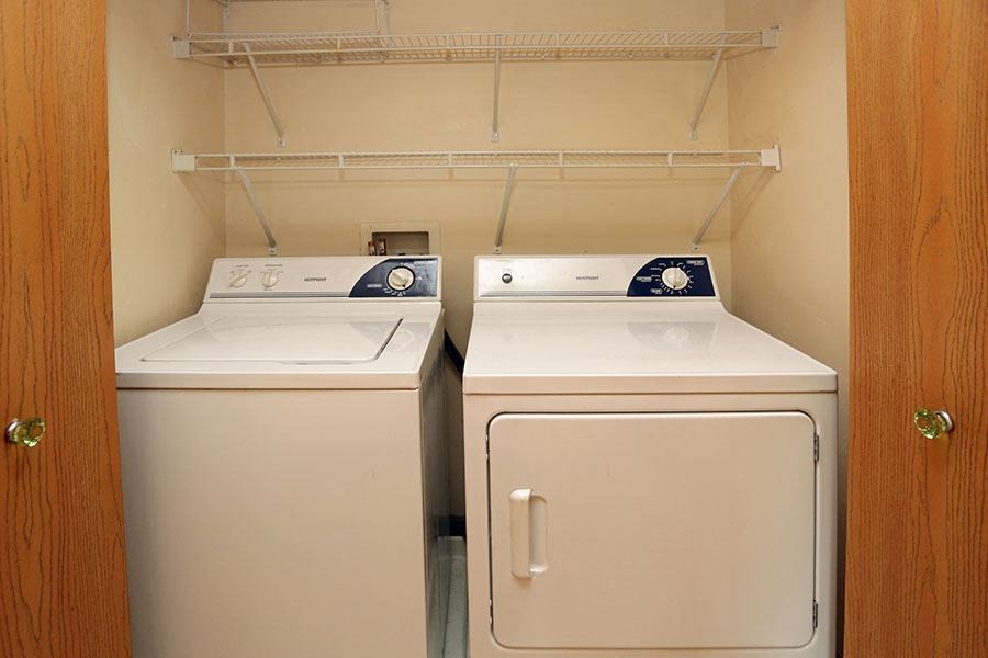 two washing machines in a room with a closet