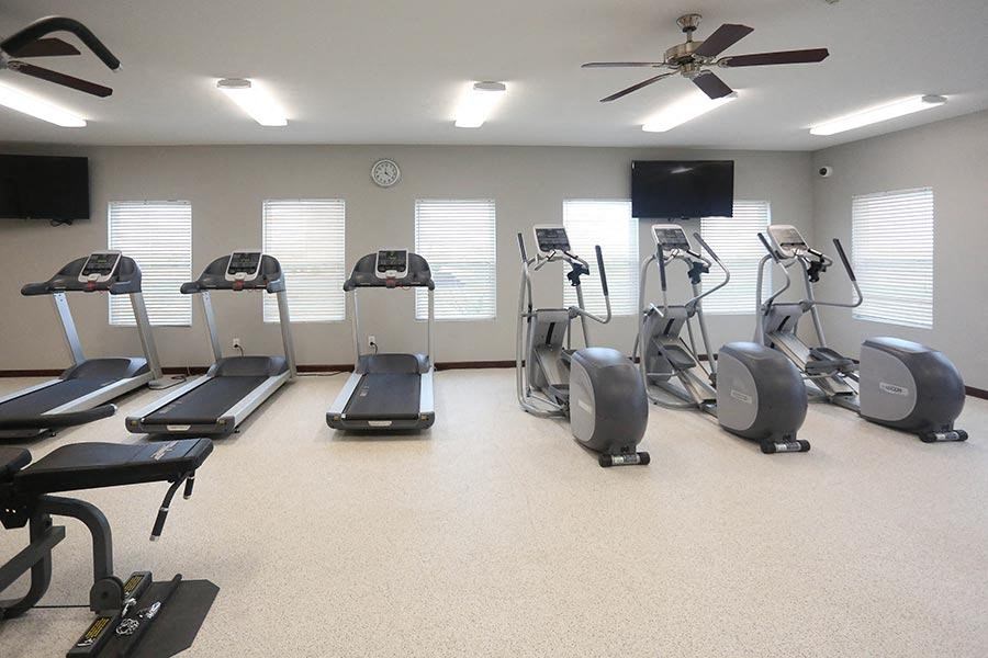 a gym with several exercise machines and a tv