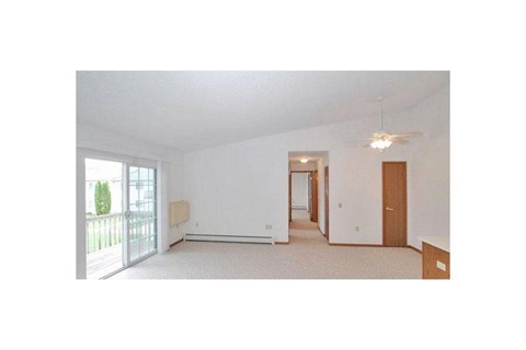 an empty living room with white walls and a balcony