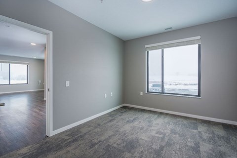 A room with a large window and a carpeted floor.