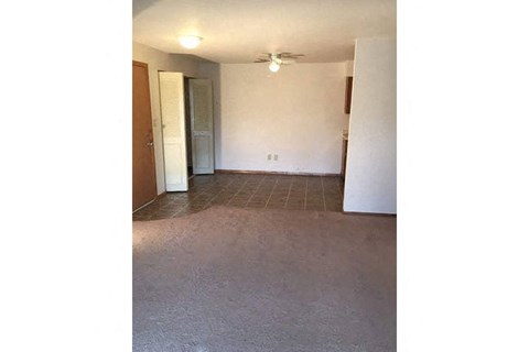 an empty living room with a ceiling fan