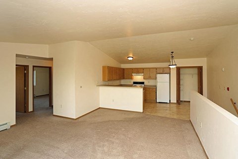 an empty living room and kitchen with a refrigerator