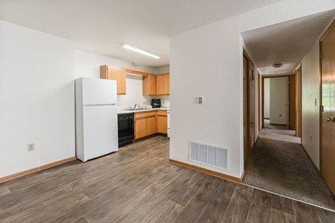 A kitchen with a white fridge and wooden floors.
