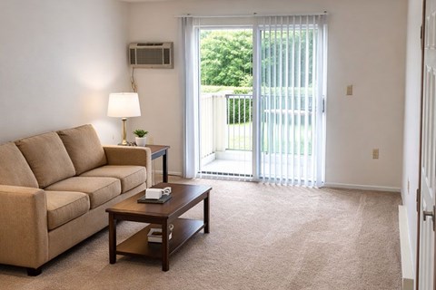 A living room with a couch, a coffee table, and a sliding glass door.