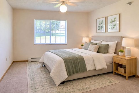 A bedroom with a bed, nightstand, and window.