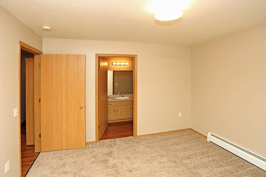 an empty living room with a door to a bathroom