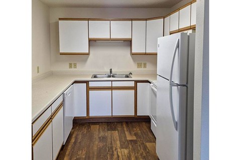 A kitchen with white cabinets and a white refrigerator.