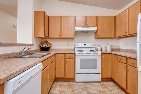 A kitchen with wooden cabinets and a white dishwasher.