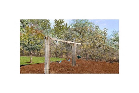 A swing set in a backyard with a wooden swing frame and two swings.