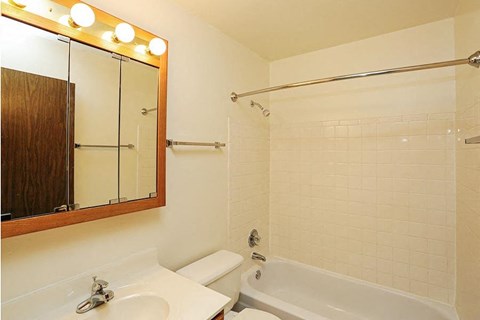 A bathroom with a white tub, sink, and mirror.