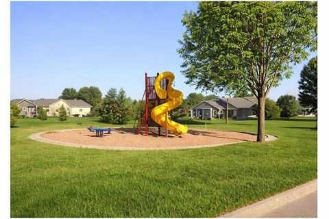 A playground with a yellow slide and a blue bench.